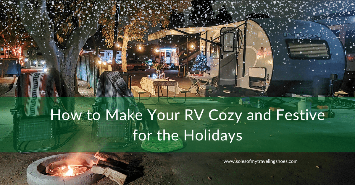 RV decorated with Christmas tree, lights, and two chairs by a campfire